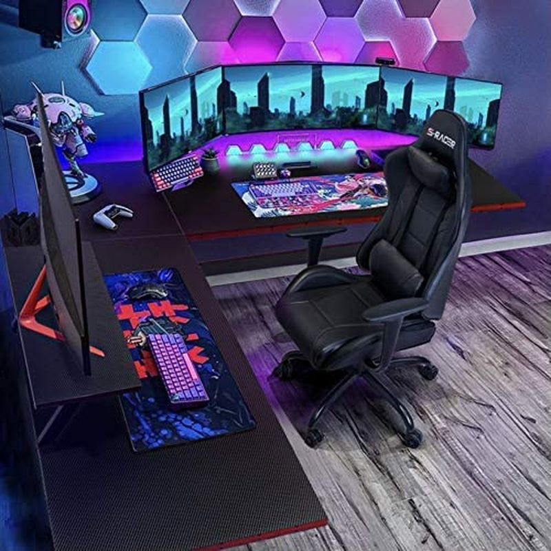L shaped gaming desk setup featuring multiple monitors, gaming keyboard, and ergonomic chair in a vibrant room.